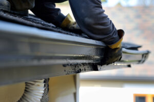 Gutter specialist installing seamless aluminum gutters along the roof cornice of a South Philly home.