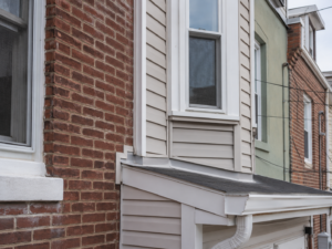 Exterior wall transition where siding meets brick masonry requiring inspection for water intrusion.