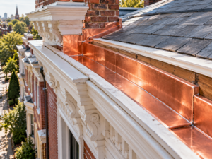 The rear exterior facade of a renovated Philadelphia rowhome featuring newly installed gray horizontal fiber cement siding with crisp white corner trim.